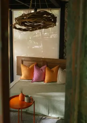 a bedroom with a bed with pillows and a table at Unique Tiny House-Best Beach in El Zonte in El Zonte