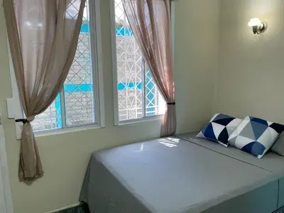 a bed in a room with two windows at Hostal primaveras nest in Santa Ana
