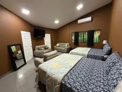 a bedroom with two beds and a couch and a tv at El Mangal 2 B&B in Suchitoto