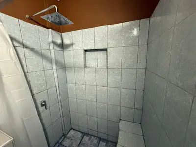 a bathroom with a shower with white tiles at El Mangal 2 B&B in Suchitoto
