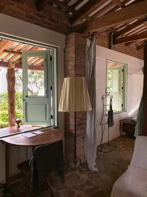 a room with a table and a lamp and windows at Finca Santa Lucía - Comasagua - Surf City Highlands in Comasagua