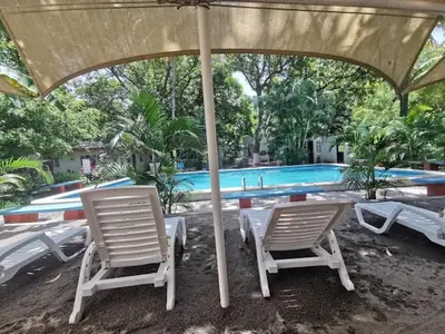 two chairs and an umbrella next to a swimming pool at Rincon del mar in La Libertad