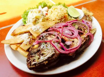 a plate of food with meat and vegetables on a table at Rincon del mar in La Libertad