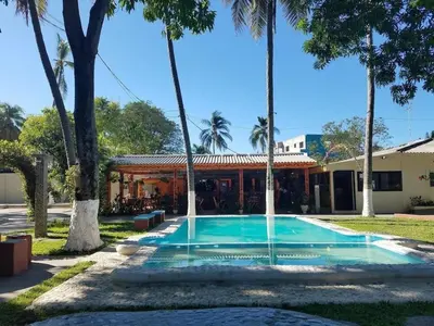 a swimming pool in front of a house with palm trees at Rincon del atardecer in La Libertad