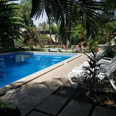 a swimming pool with two white chairs and a palm tree at Rincon del atardecer in La Libertad