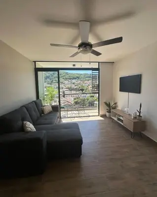 a living room with a couch and a ceiling fan at Cielito Lindo, vista espectacular en 11 nivel in Antiguo Cuscatlán