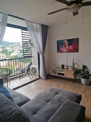 a living room with a couch and a flat screen tv at Cielito Lindo, vista espectacular en 11 nivel in Antiguo Cuscatlán