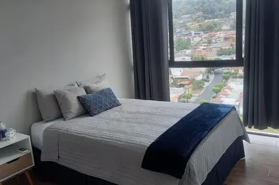 a bedroom with a bed with a large window at Cielito Lindo, vista espectacular en 11 nivel in Antiguo Cuscatlán
