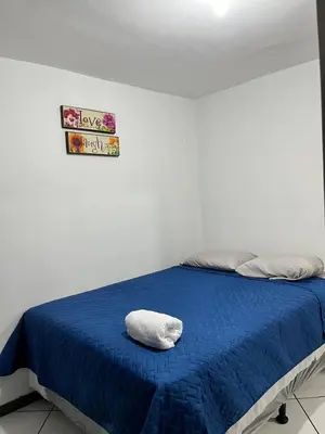 a bed with a blue blanket and a sign on the wall at Todo cerca Apartamento Familiar en el corazón de San Salvador in San Salvador