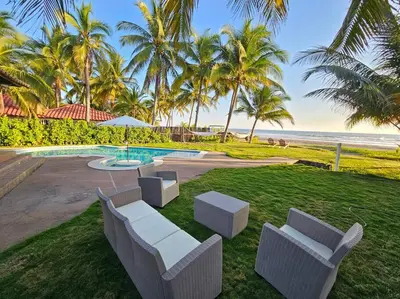 a resort yard with two white chairs and a pool at Villa San Juan, playa Costa Azul in Acajutla