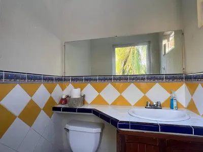 a bathroom with a sink and a mirror and a toilet at Villa San Juan, playa Costa Azul in Acajutla