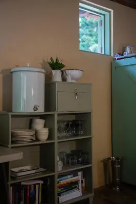 a green book shelf with plates and dishes on it at Finca Life - Surf City Highlands - Comasagua in Los Amates