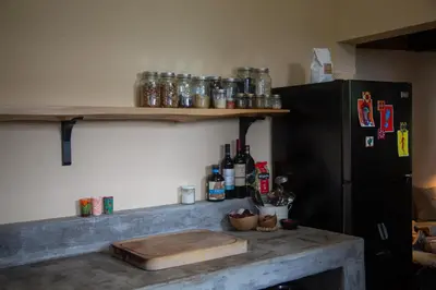 a kitchen with a counter with a refrigerator and shelves at Finca Life - Surf City Highlands - Comasagua in Los Amates