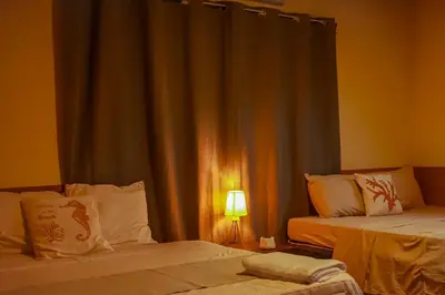 a room with two beds and a window with a lamp at Coral Beach in Tamanique