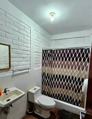 a bathroom with a white toilet and a sink at Jaco Mizata Beach and River in Las Piedras
