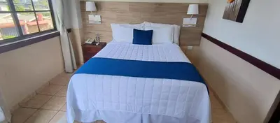 a bedroom with a bed with a blue pillow on it at Hotel Alicante San Salvador in Antiguo Cuscatlán