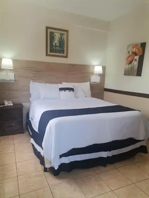 a hotel room with a large bed and two lamps at Hotel Alicante San Salvador in Antiguo Cuscatlán