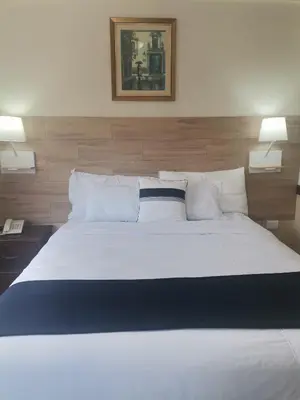 a bedroom with a large white bed with two lamps at Hotel Alicante San Salvador in Antiguo Cuscatlán