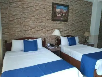 two beds in a hotel room with blue and white at Hotel Alicante San Salvador in Antiguo Cuscatlán