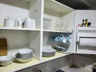 a white cabinet filled with plates and dishes at Casita Jardin in San Salvador