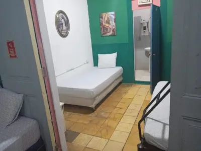 a small room with a white bed and green walls at Hostal Brunette Santein in Santa Ana