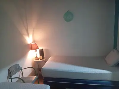 a bedroom with a bed and a lamp and a chair at Hostal Brunette Santein in Santa Ana