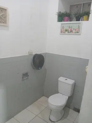 a bathroom with a toilet in a white tiled wall at Hostal Brunette Santein in Santa Ana