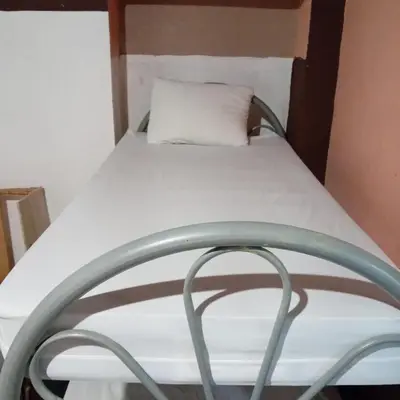 a bed in a small room with a pillow on it at Hostal Brunette Santein in Santa Ana
