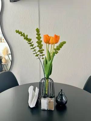 a vase with orange flowers sitting on a table at La Casita del Viajero in Santa Ana