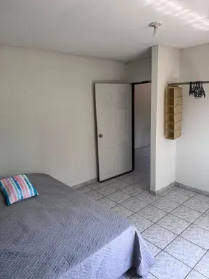 a white bedroom with a bed and a door at Nawa Kalli Surf House in El Sunzal