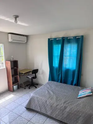 a bedroom with a bed with blue curtains and a desk at Nawa Kalli Surf House in El Sunzal