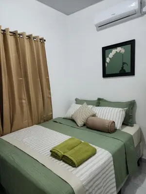a bedroom with a large bed with green and white sheets at Casa Villa El Escape en Residencial Villa Panamericana in San Miguel