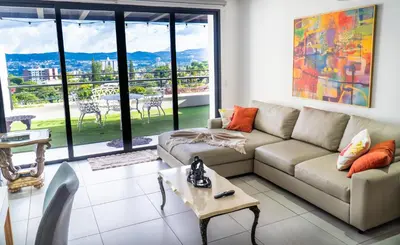 a living room with a couch and a table at Brisa Serena Apartamento con parqueo y gran terraza en La Escalón in San Salvador