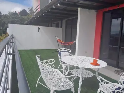 a patio with a table and chairs on a balcony at Brisa Serena Apartamento con parqueo y gran terraza en La Escalón in San Salvador