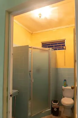 a bathroom with a toilet and a glass shower at Hostal Casa Luna in Santa Ana