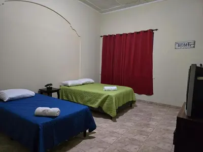 a room with two beds and a red curtain at Hostal Casa Luna in Santa Ana