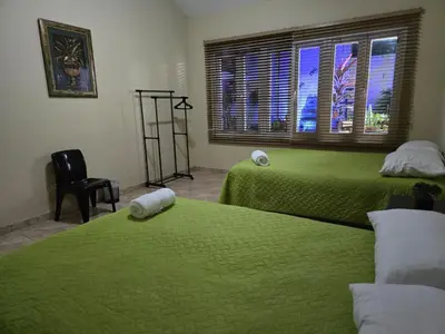 a bedroom with two green beds and a window at Hostal Casa Luna in Santa Ana