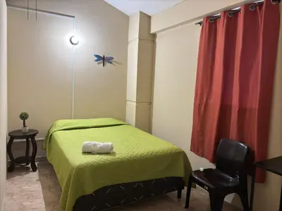 a bedroom with a green bed and a chair at Hostal Casa Luna in Santa Ana