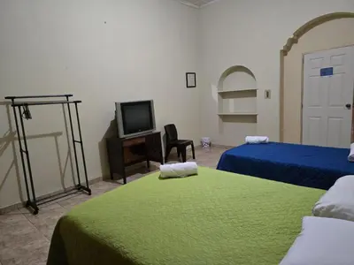 a room with two beds and a tv and a room with a bedskirts at Hostal Casa Luna in Santa Ana