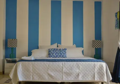 a bedroom with a bed with blue and white stripes at Casa Coral in Los Cóbanos