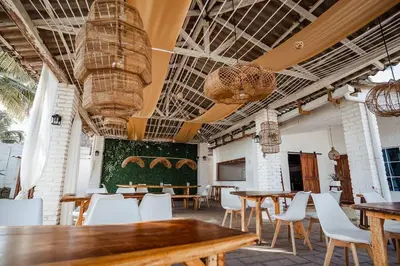 a restaurant with wooden tables and white chairs at Cabo in Las Hojas