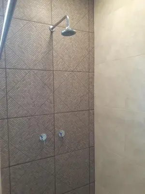 a shower with a glass door with a shower head at Charlys Place in San Salvador