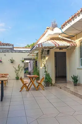 a patio with benches and tables on a house at Hostal CASA LUNA in Santa Ana