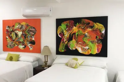 a room with two beds and paintings on the wall at Casa Las Doroteo in El Sunzal