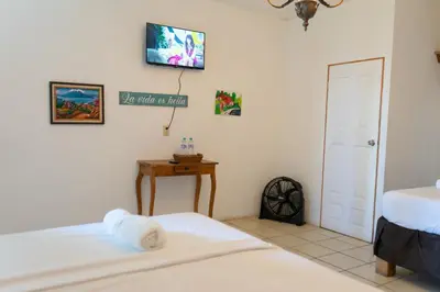 a bedroom with two beds and a tv on the wall at Las Cabañitas in San Salvador