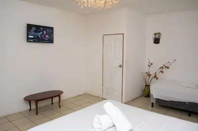 a white bedroom with a bed and a table at Las Cabañitas in San Salvador