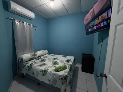 a blue room with a bed and a tv at Casa en Nueva Metropolis con aire en toda la casa in San Miguel
