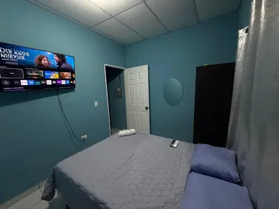 a bedroom with a bed and a tv on the wall at Casa en Nueva Metropolis con aire en toda la casa in San Miguel