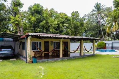 a small house with a hammock in a yard at Rancho El Ancla Surf City Wi-Fi AC Pool in La Libertad
