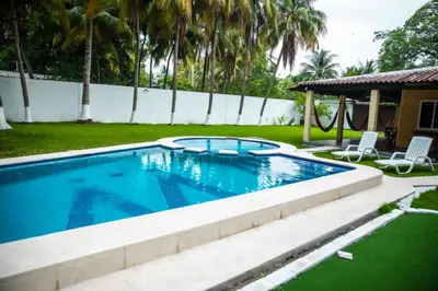 a swimming pool in a yard with two lawn chairs at Rancho El Ancla Surf City Wi-Fi AC Pool in La Libertad